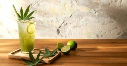 Image of a Delta-9 drink in a glass with some hemp leaves and lemon beside it.